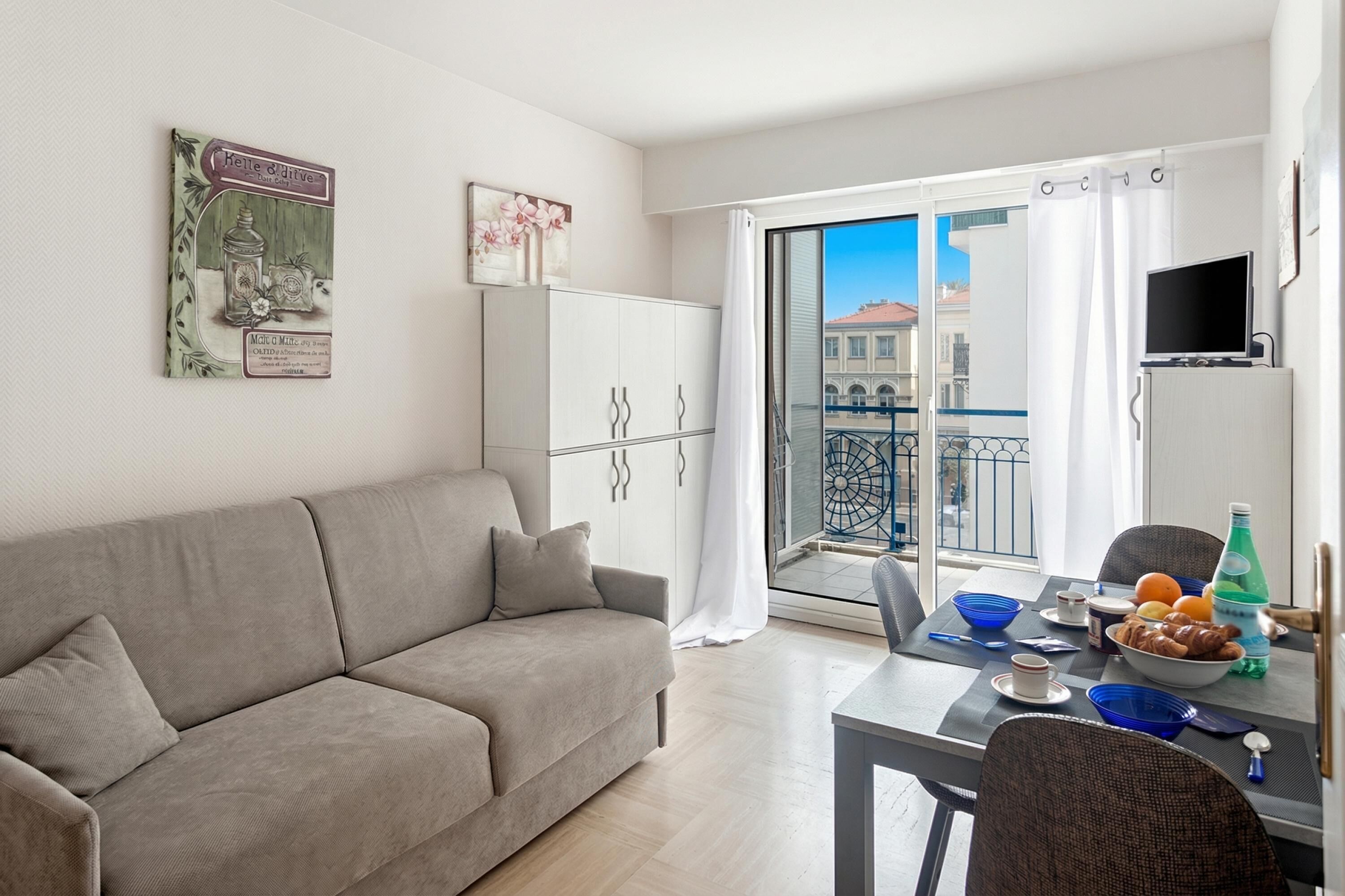 Un salon moderne avec un canapé, une table à manger et un balcon offrant une vue agréable.
