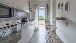 A modern kitchen with a central island, a dining area with a chair, and a balcony with a view.