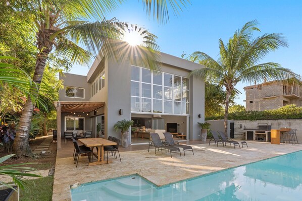 A modern house with a pool, outdoor seating, and a covered patio.
