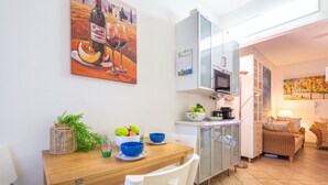 A compact kitchen with a dining area, a microwave, and a coffee maker on the counter. - Oleandro by Interhome (Villasimius)