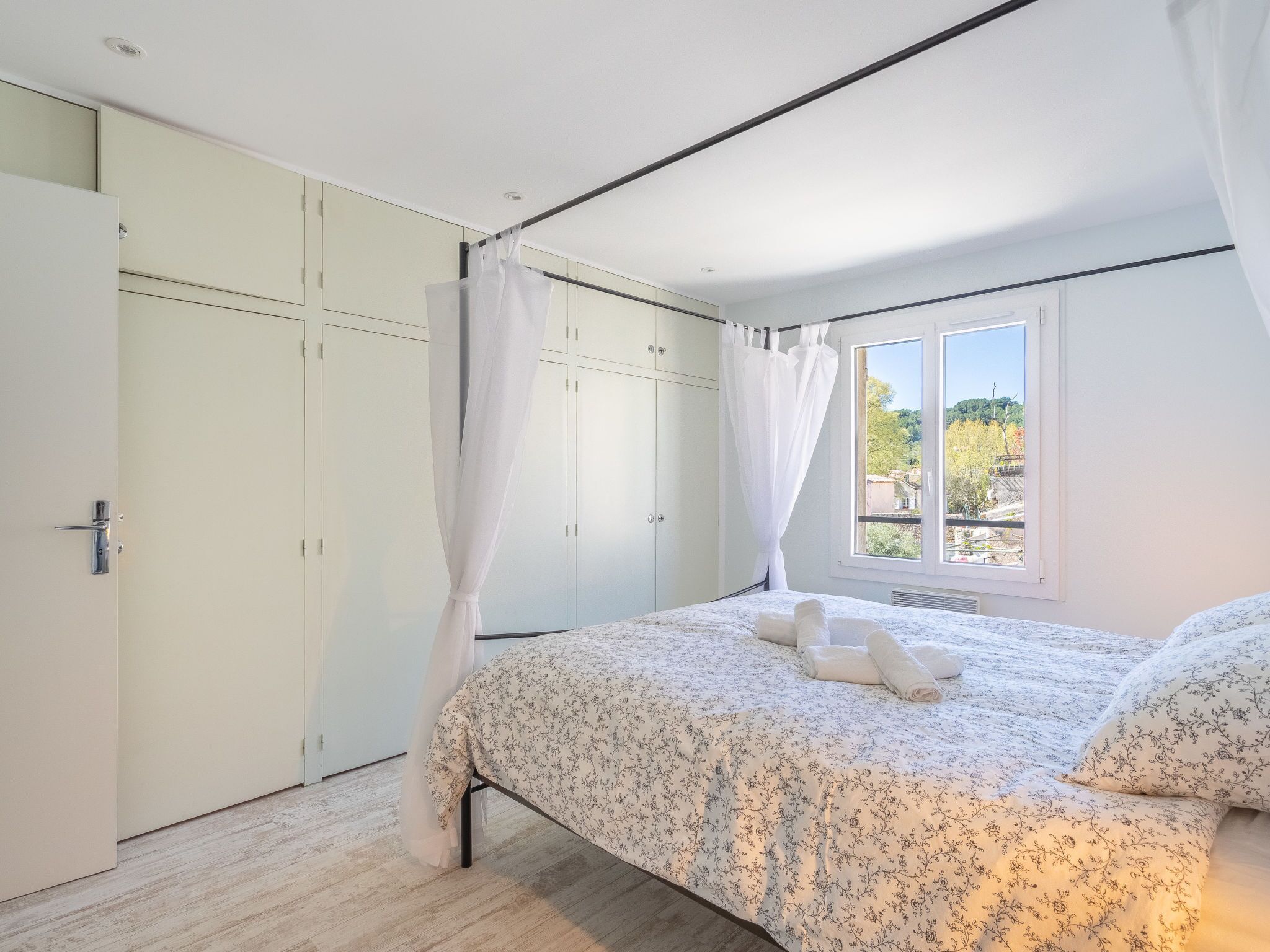 Une chambre à coucher avec un lit, une fenêtre donnant sur un beau paysage et une armoire.
