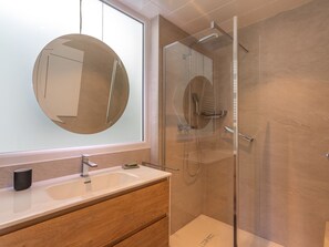 A modern bathroom with a round mirror, a sink, and a glass-enclosed shower. - La Quiètude by Interhome (Le Beausset / Saint Anne d'Evenos)