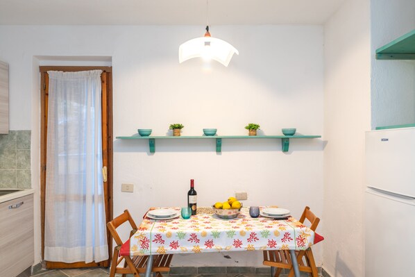 A dining area with a table set for two, a wine bottle, and a bowl of lemons.