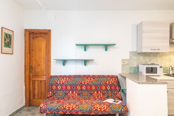Una pequeña cocina americana con microondas, una puerta de madera y un banco colorido.