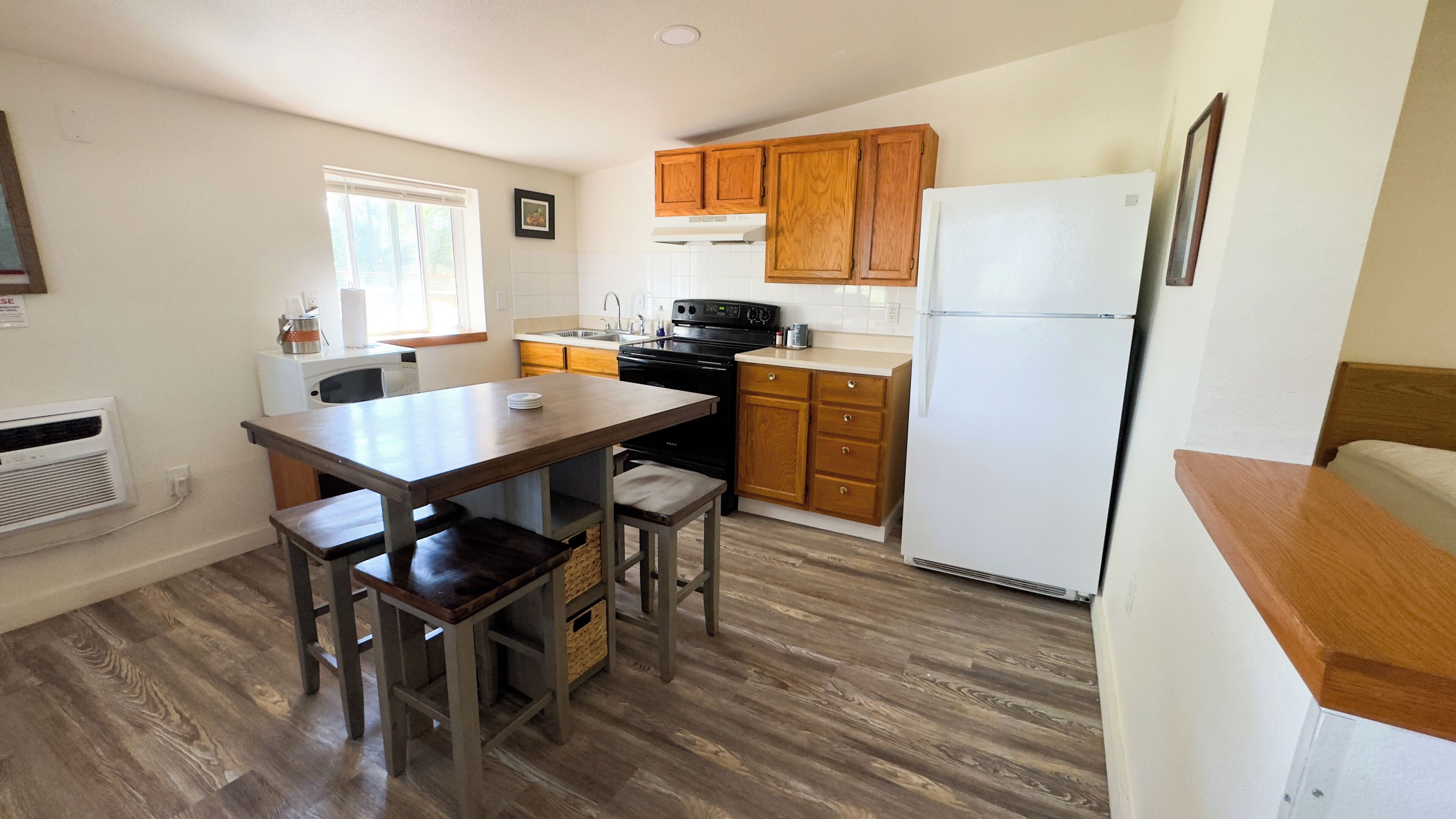Una cocina compacta con armarios de madera, estufa negra y refrigerador blanco.