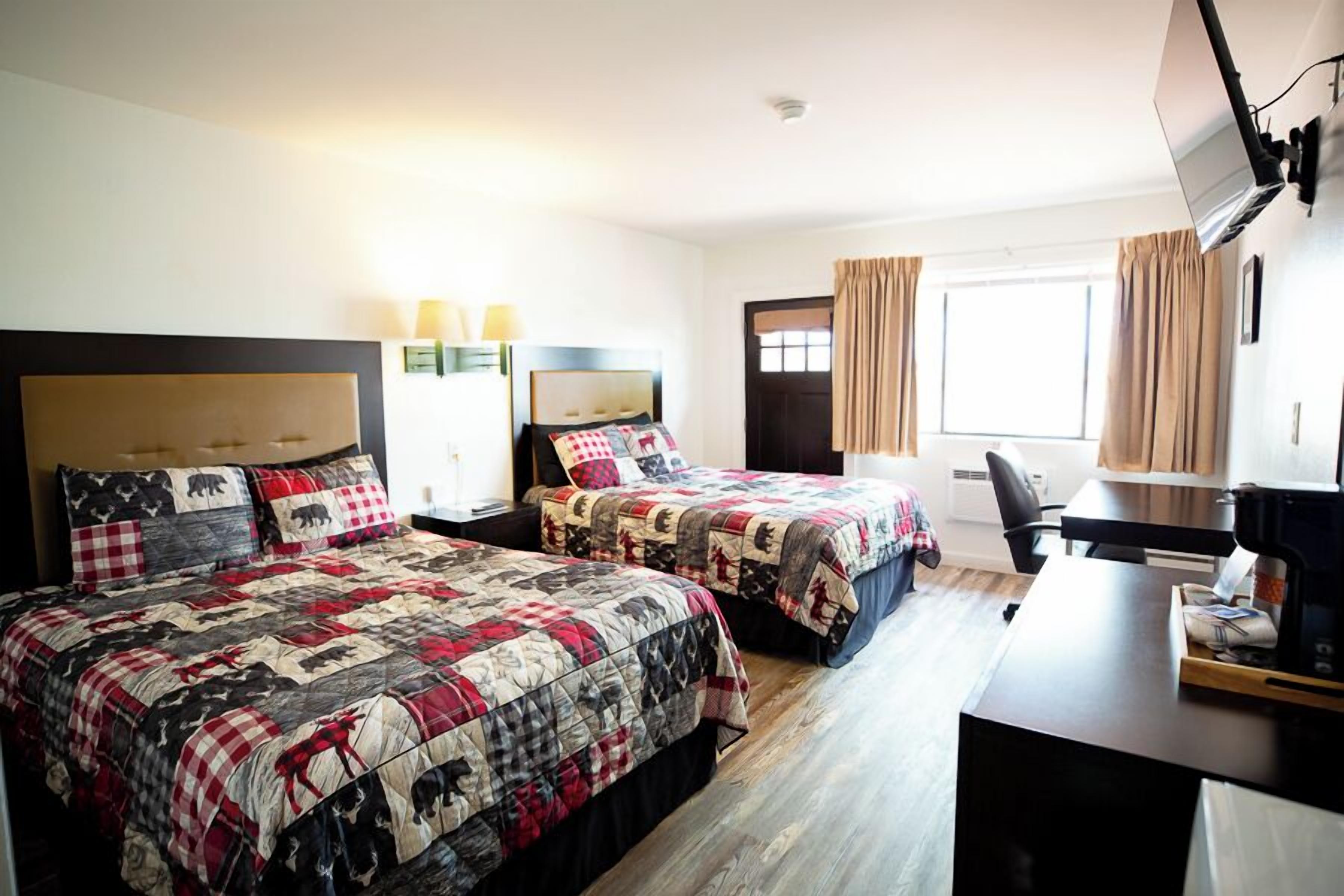 A hotel room with two beds, a desk, and a TV.