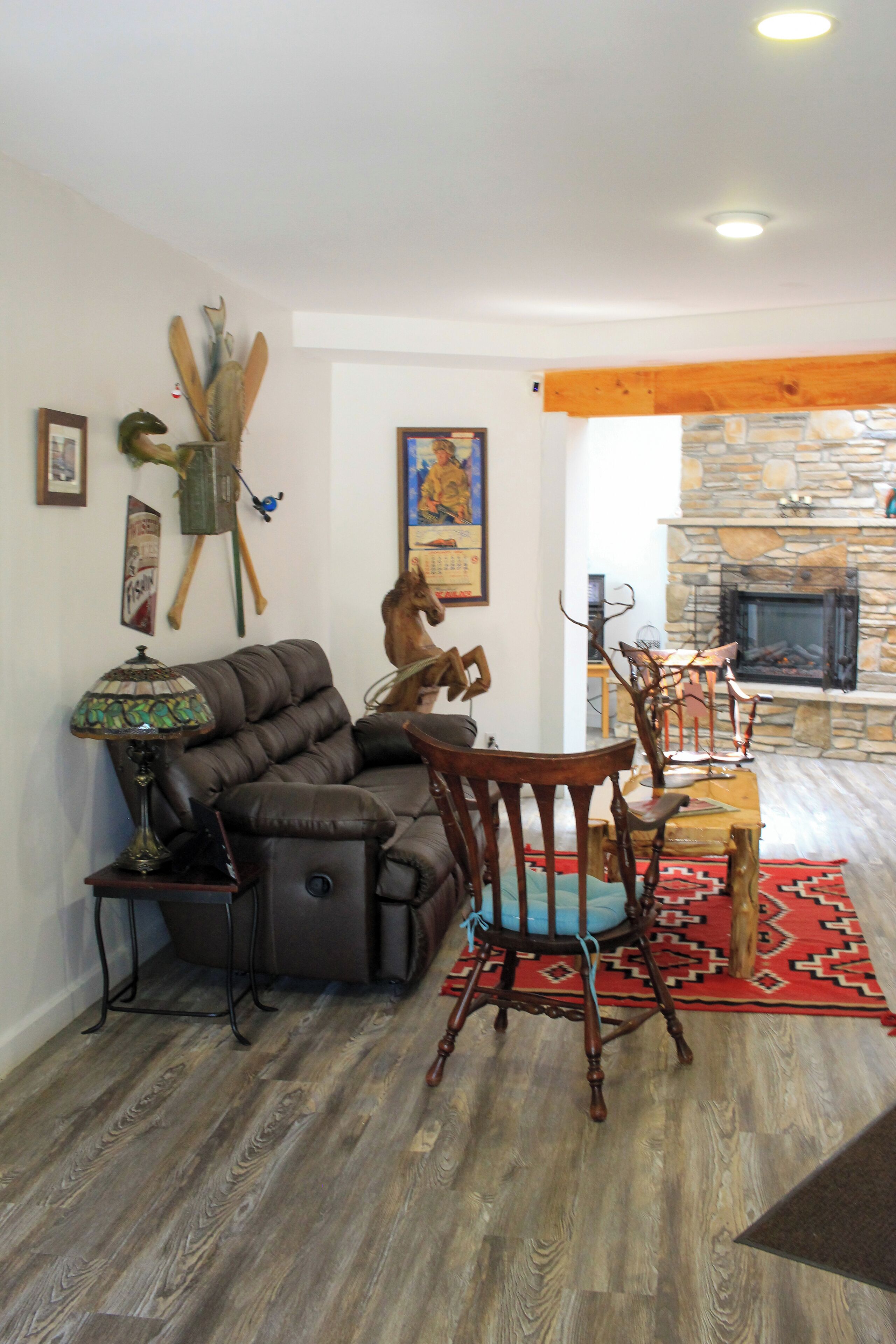 A living room with a stone fireplace, leather sofa, wooden dining table, and chairs.