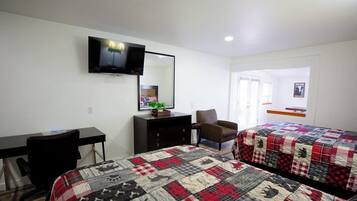 Une chambre d’hôtel avec deux lits, un bureau, une chaise, une télévision et une commode.