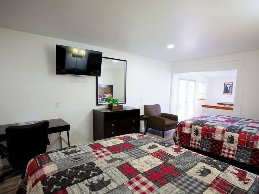Une chambre d’hôtel avec deux lits, un bureau, une chaise, une télévision et une commode.