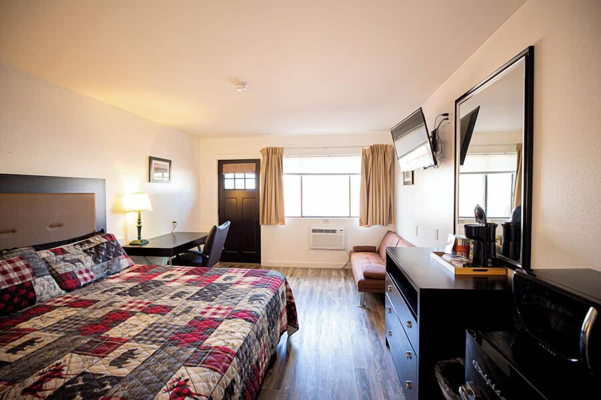 Ein Hotelzimmer mit einem großen Bett, einem Schreibtisch, einem Schminktisch und einem Fernseher.