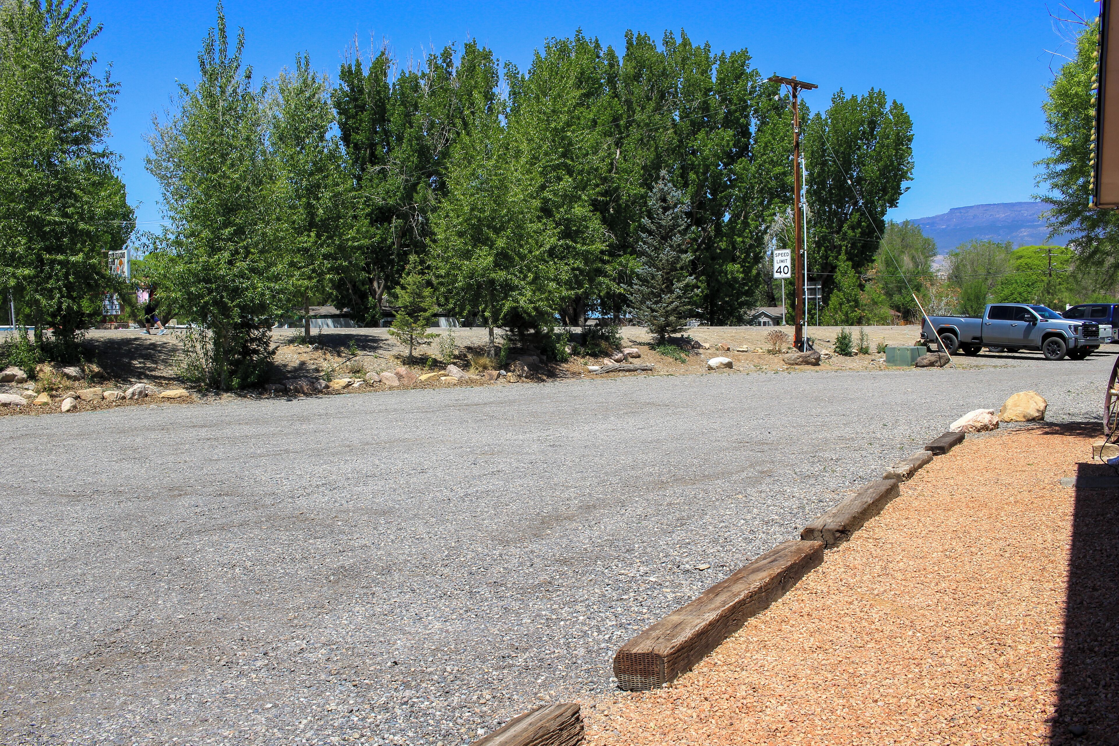 A paved road with a gravel shoulder, surrounded by trees and a mountain in the background.