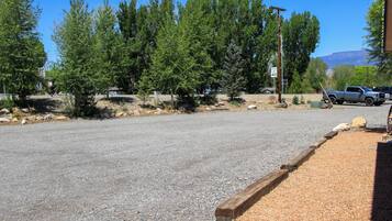A paved road with a gravel shoulder, surrounded by trees and a mountain in the background.