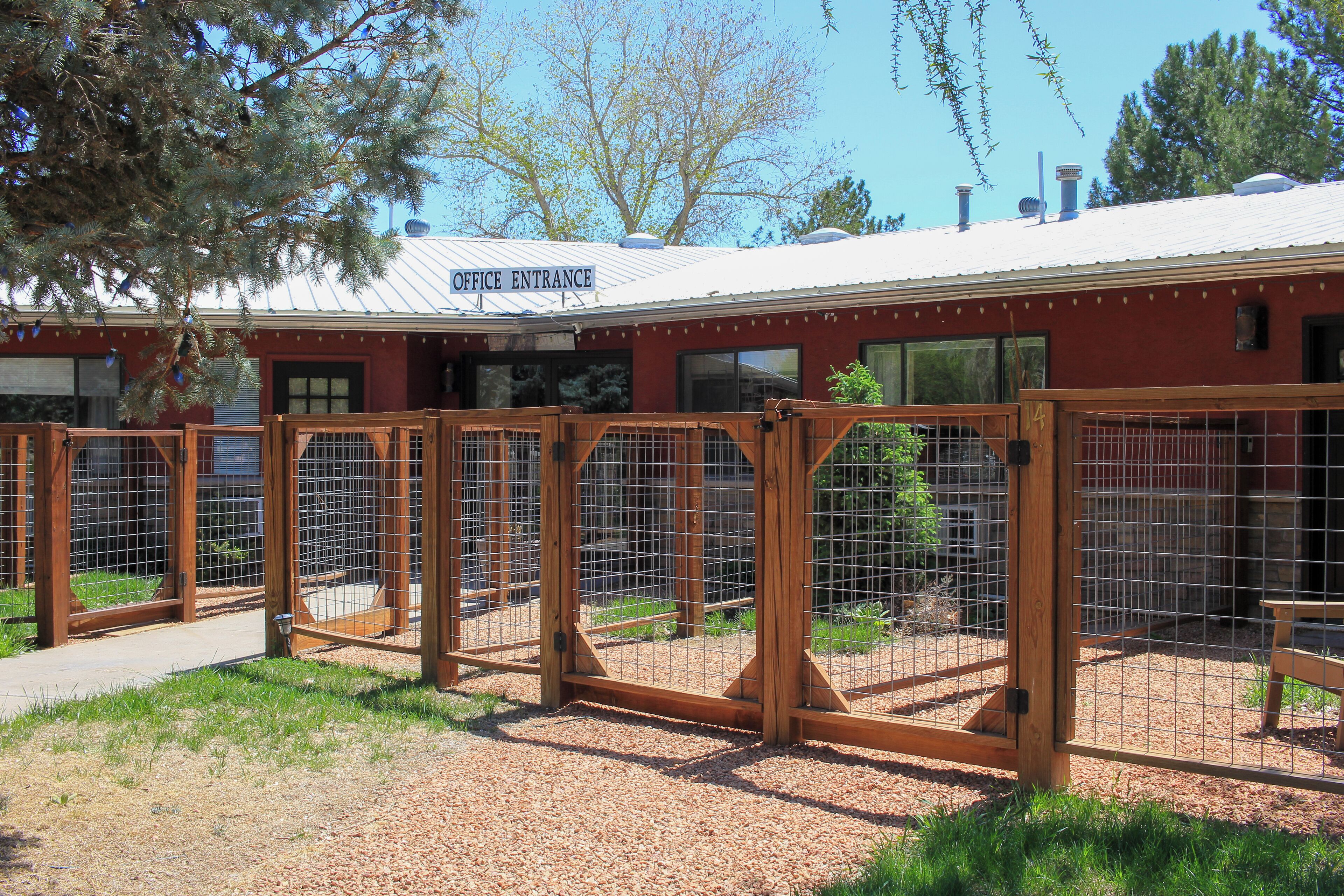 A building with an office entrance sign, wooden gates, and a fenced area with a bench.