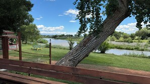 A wooden bench, a picnic table, and a gazebo by a river.