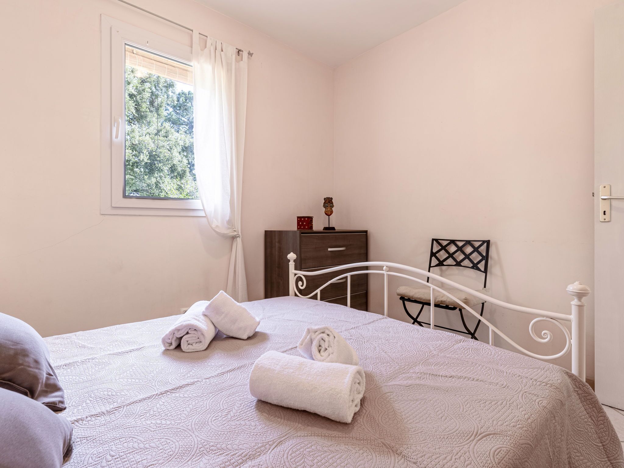 A bedroom with a bed, a nightstand, a dresser, and a window with curtains.