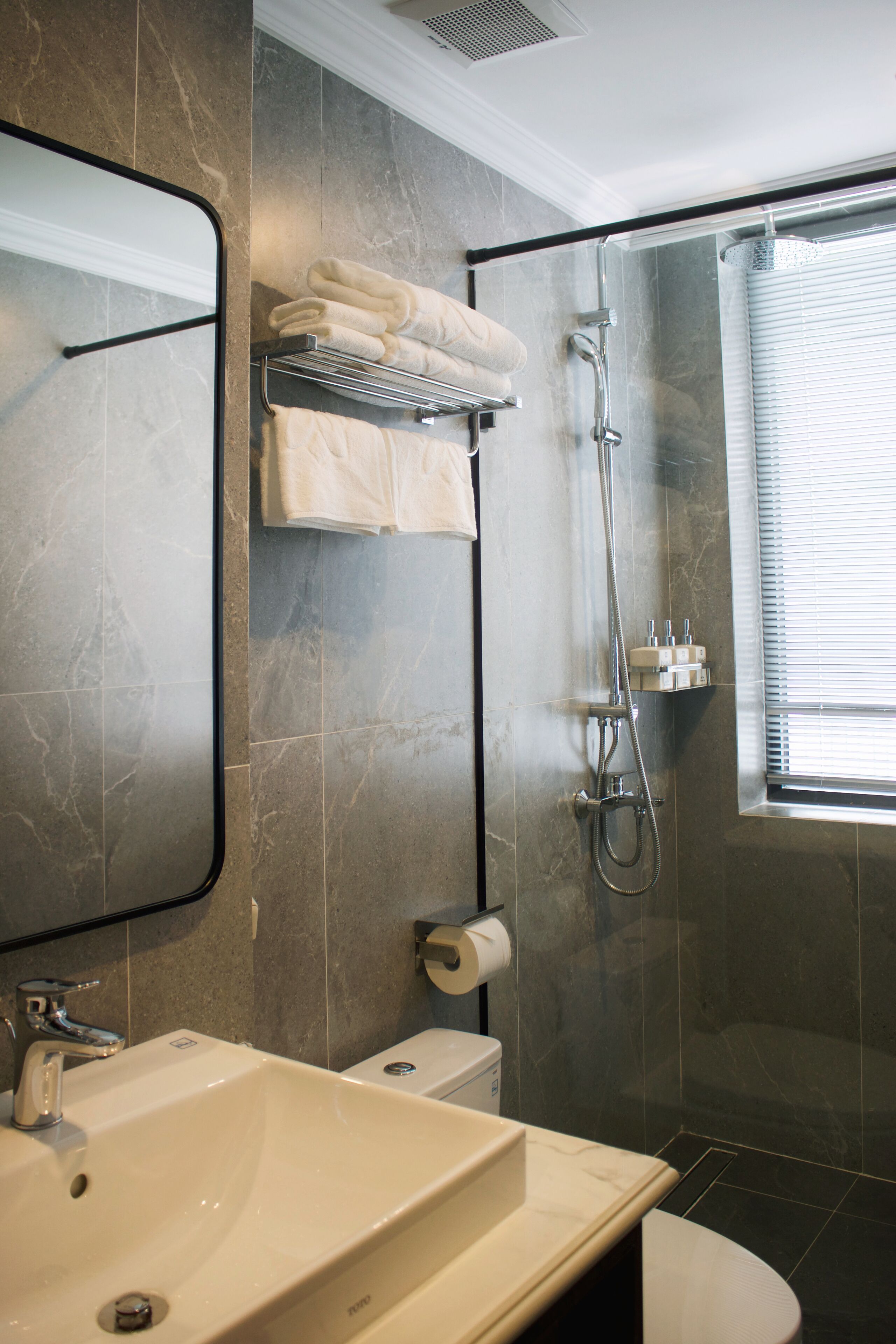 A bathroom with a large sink, mirror, towel rack, shower, and toilet.