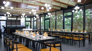 A spacious dining area with multiple tables and chairs, large windows, and hanging light fixtures. - Indigen Boutique Hotel Cao Bang (Thuc Phan)