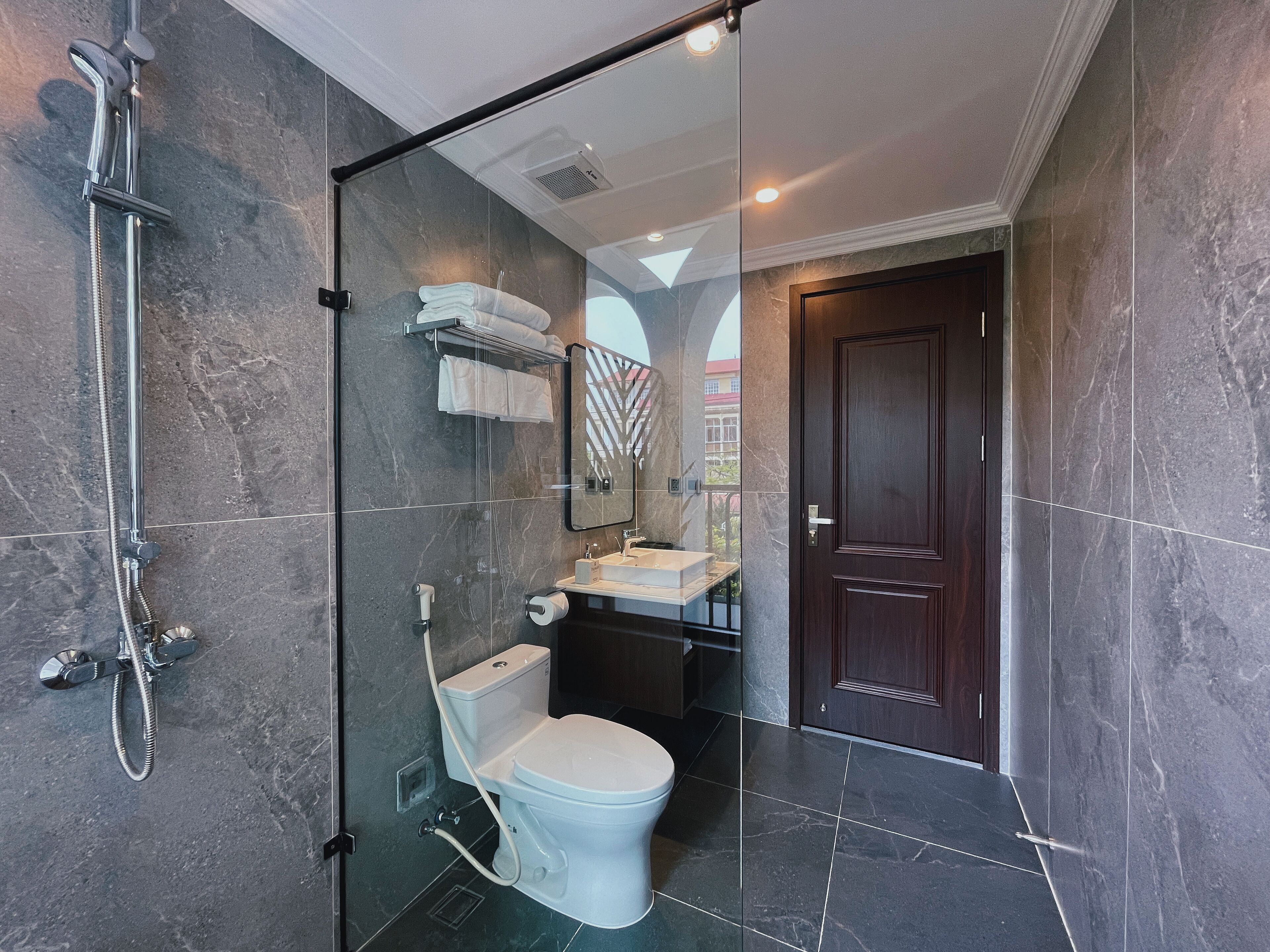 A modern bathroom with a glass-enclosed shower, a toilet, and a sink.