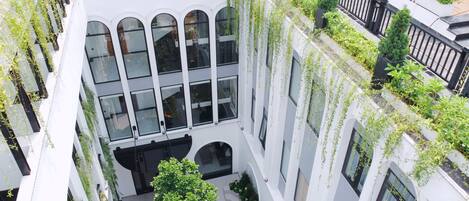 A multi-story building with large windows, a central courtyard, and greenery.