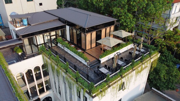A modern building with a rooftop terrace featuring outdoor seating and greenery. - Indigen Boutique Hotel Cao Bang (Thuc Phan)