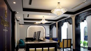 A modern hotel lobby with a reception desk, seating area, and a chandelier.