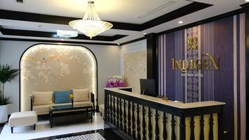 A reception area with a sofa, a reception desk, and a chandelier.