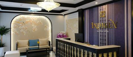 A reception area with a sofa, a reception desk, and a chandelier.