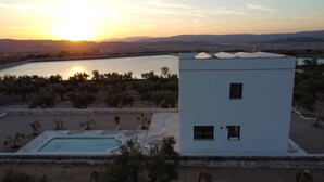 Ein modernes Gebäude mit Pool und Blick auf den Sonnenuntergang über einem See und Hügeln.