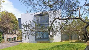 A modern building with a flat roof, large windows, and a satellite dish. - 1970's Retro style 2 bed unit (Auckland)