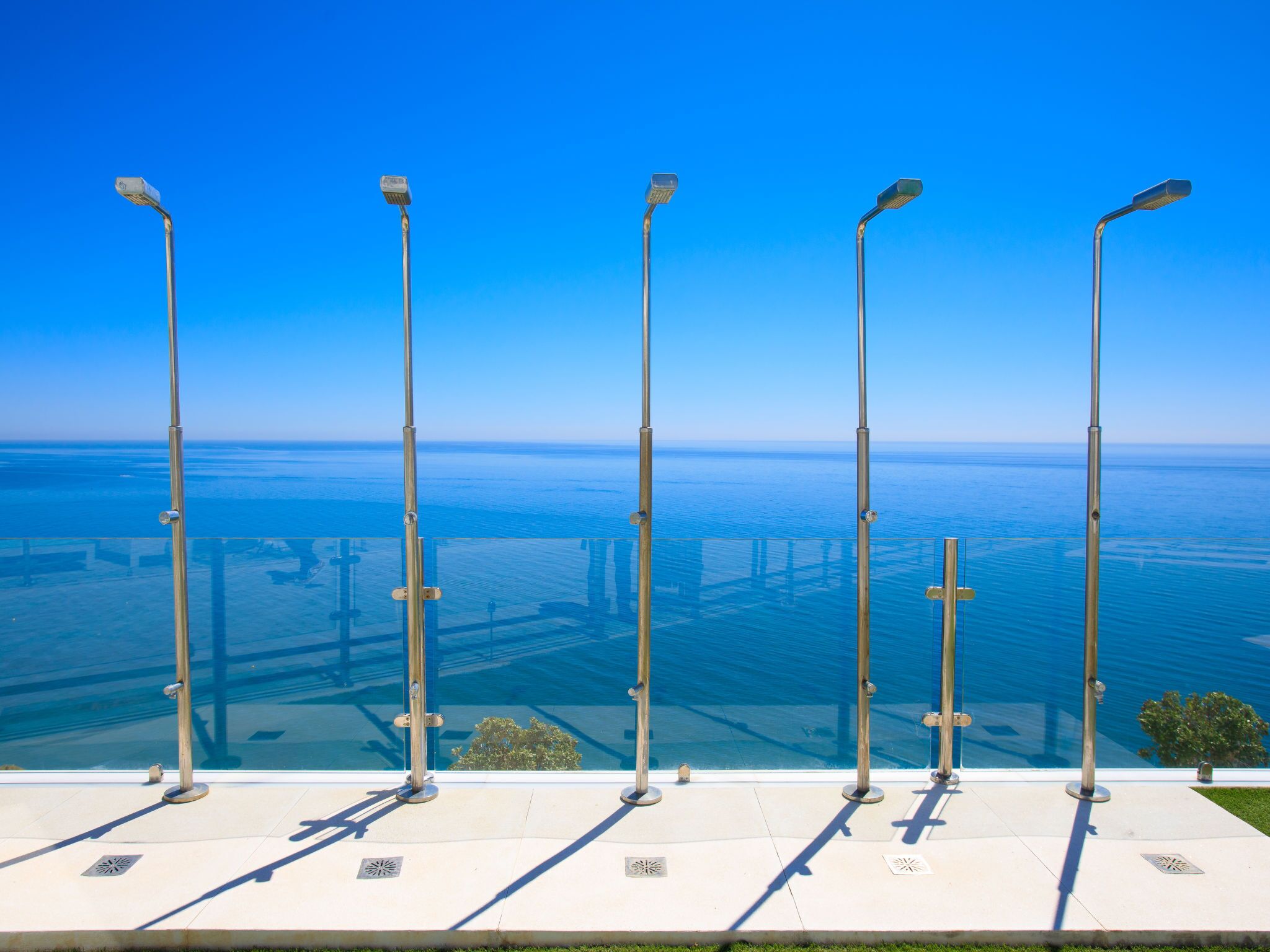 A clear view of the ocean from a high vantage point with street lamps and a paved walkway.