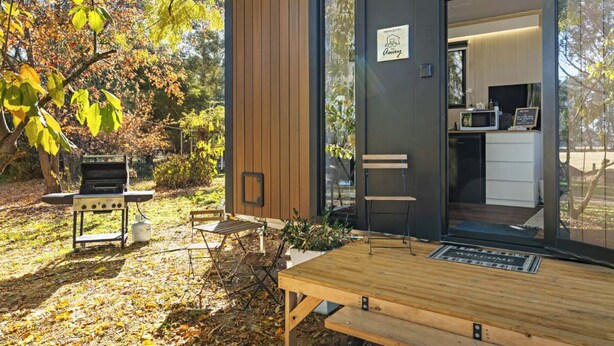 Un espacio moderno de cocina al aire libre con una parrilla, una mesa de comedor y sillas.