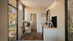 Una habitación compacta y moderna con cama, un escritorio pequeño y kitchenette.