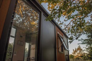 Un bâtiment moderne doté de grandes fenêtres, d’une façade en bois et offrant une vue sur les arbres.