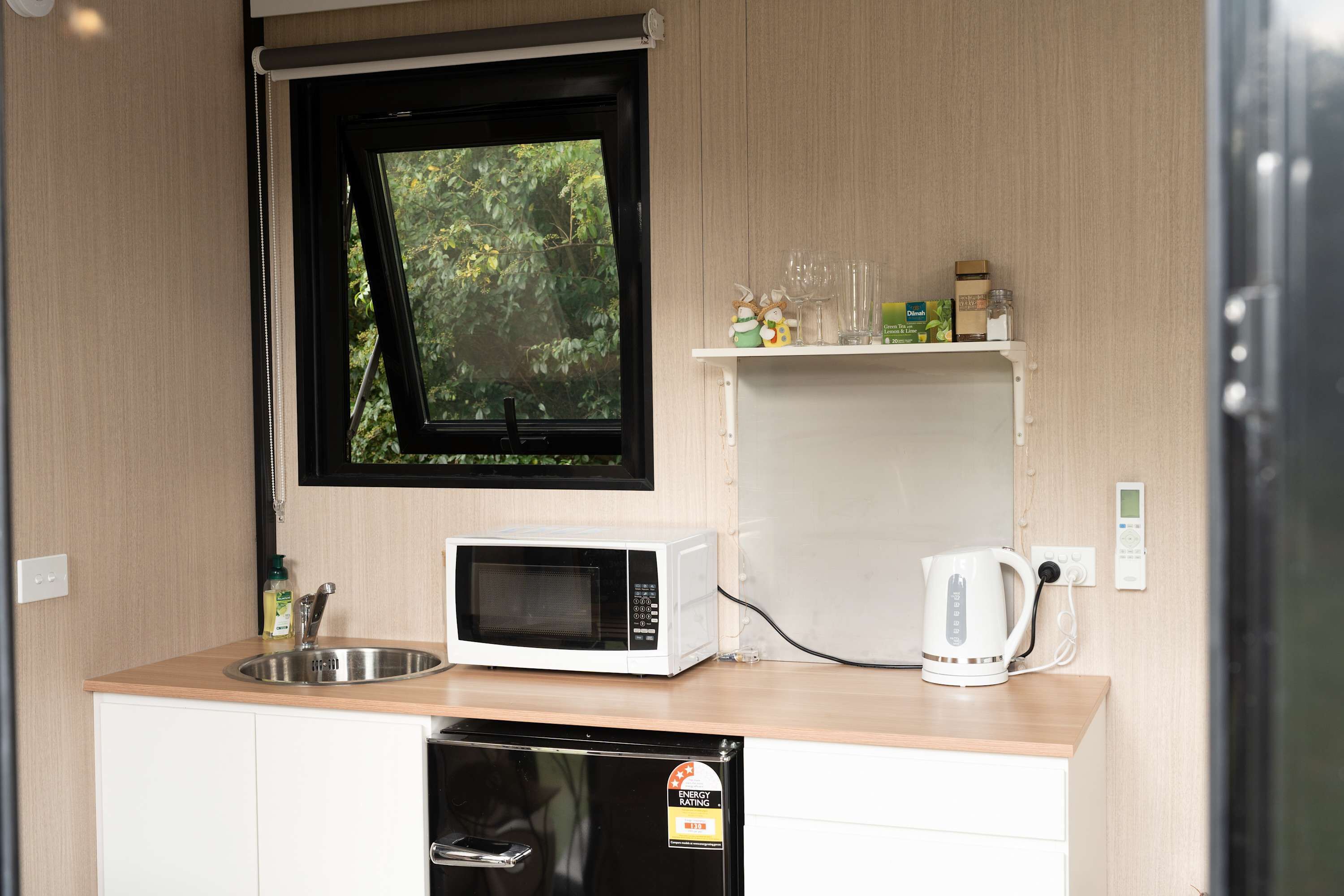 A compact kitchenette with a microwave, kettle, and sink.