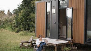 A modern cabin with a wooden deck, a bench, and a table.