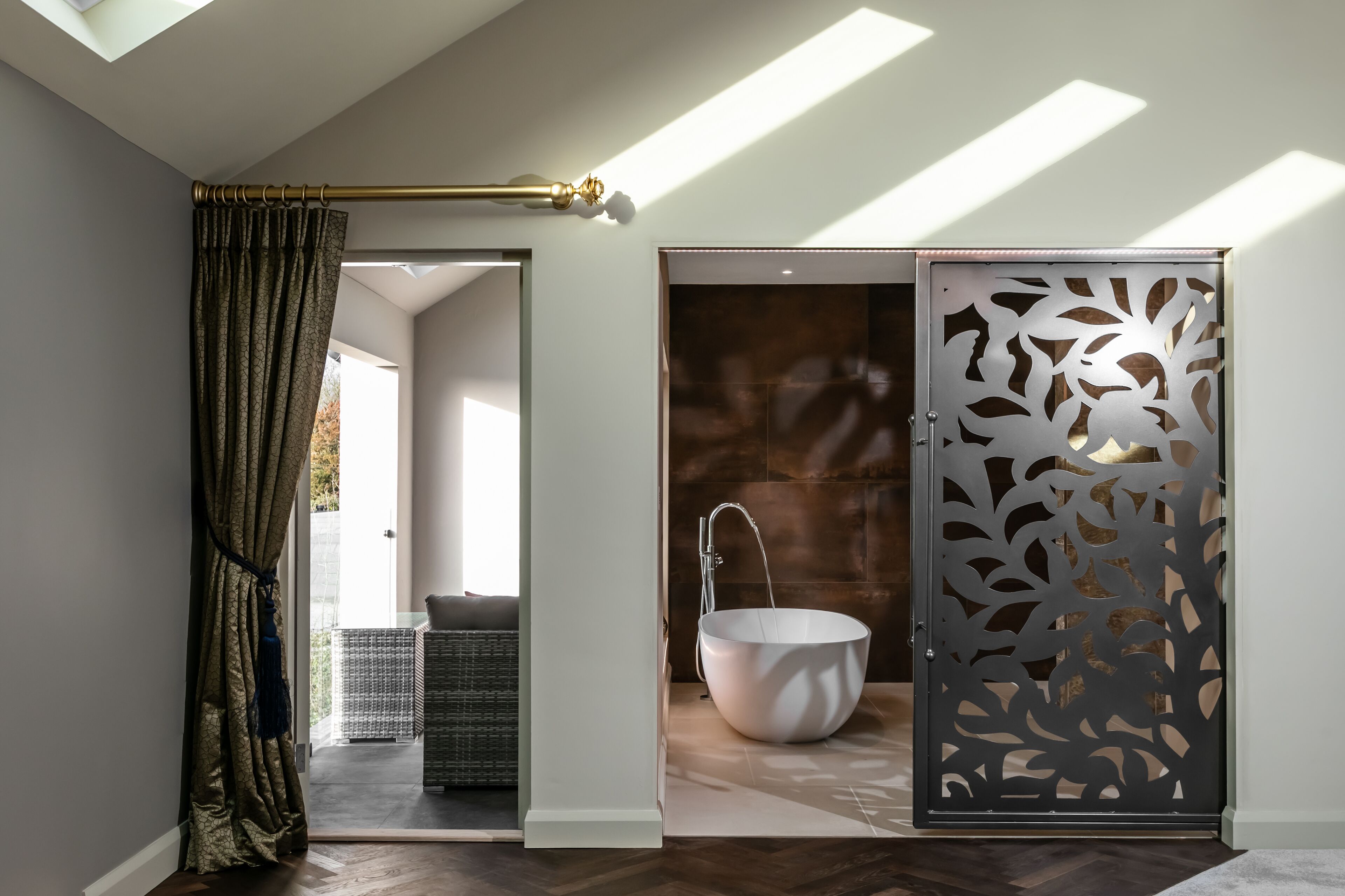 A modern bathroom with a freestanding bathtub, a decorative screen, and a skylight.