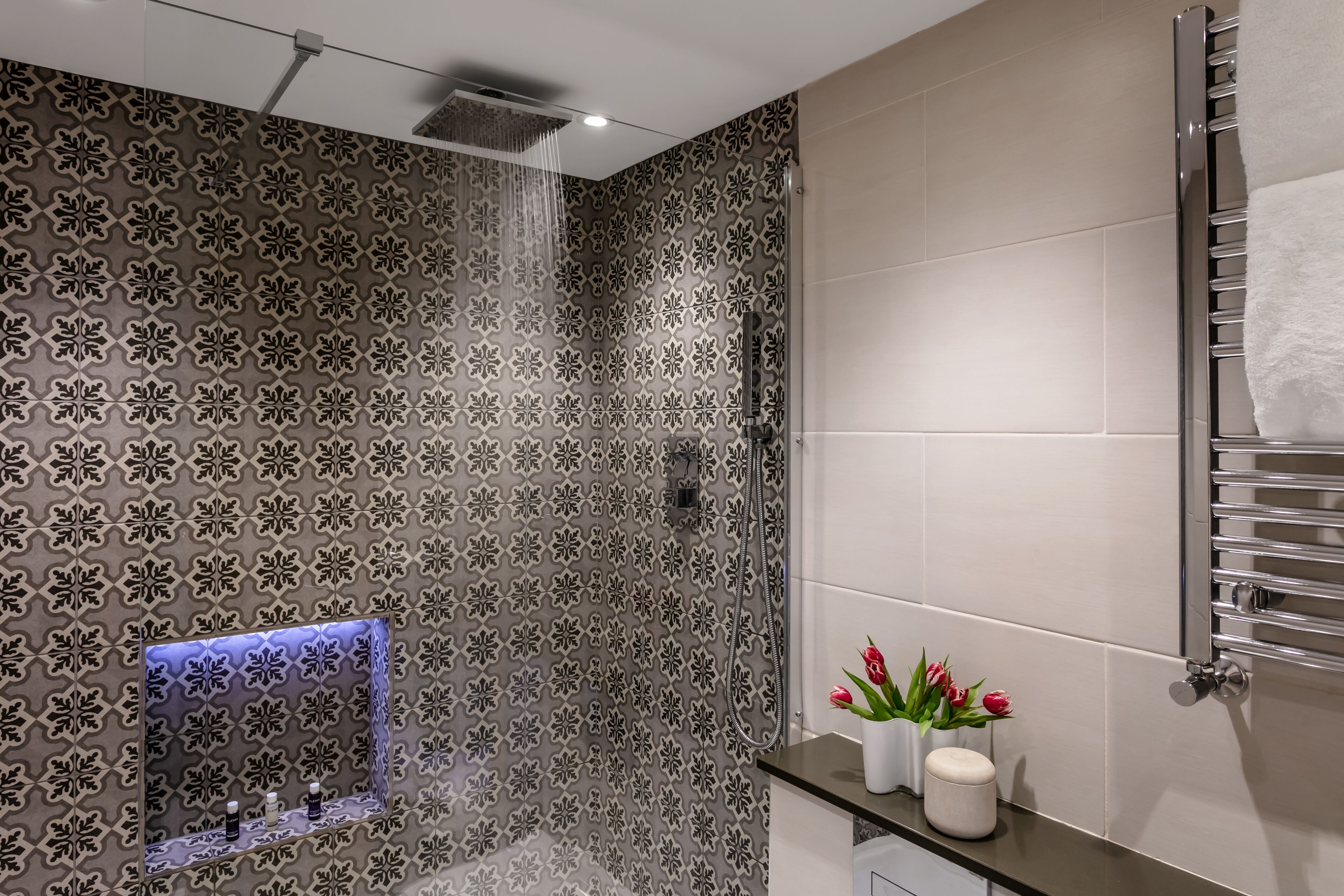 A modern bathroom with a shower, a built-in sink, and a towel rack.
