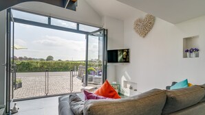 Un salon moderne avec un canapé gris, un téléviseur à écran plat et un élément de décoration murale en forme de cœur.