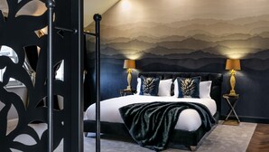 Une chambre à coucher avec un lit, deux tables de chevet avec des lampes, un mur décoratif et un luminaire au plafond.