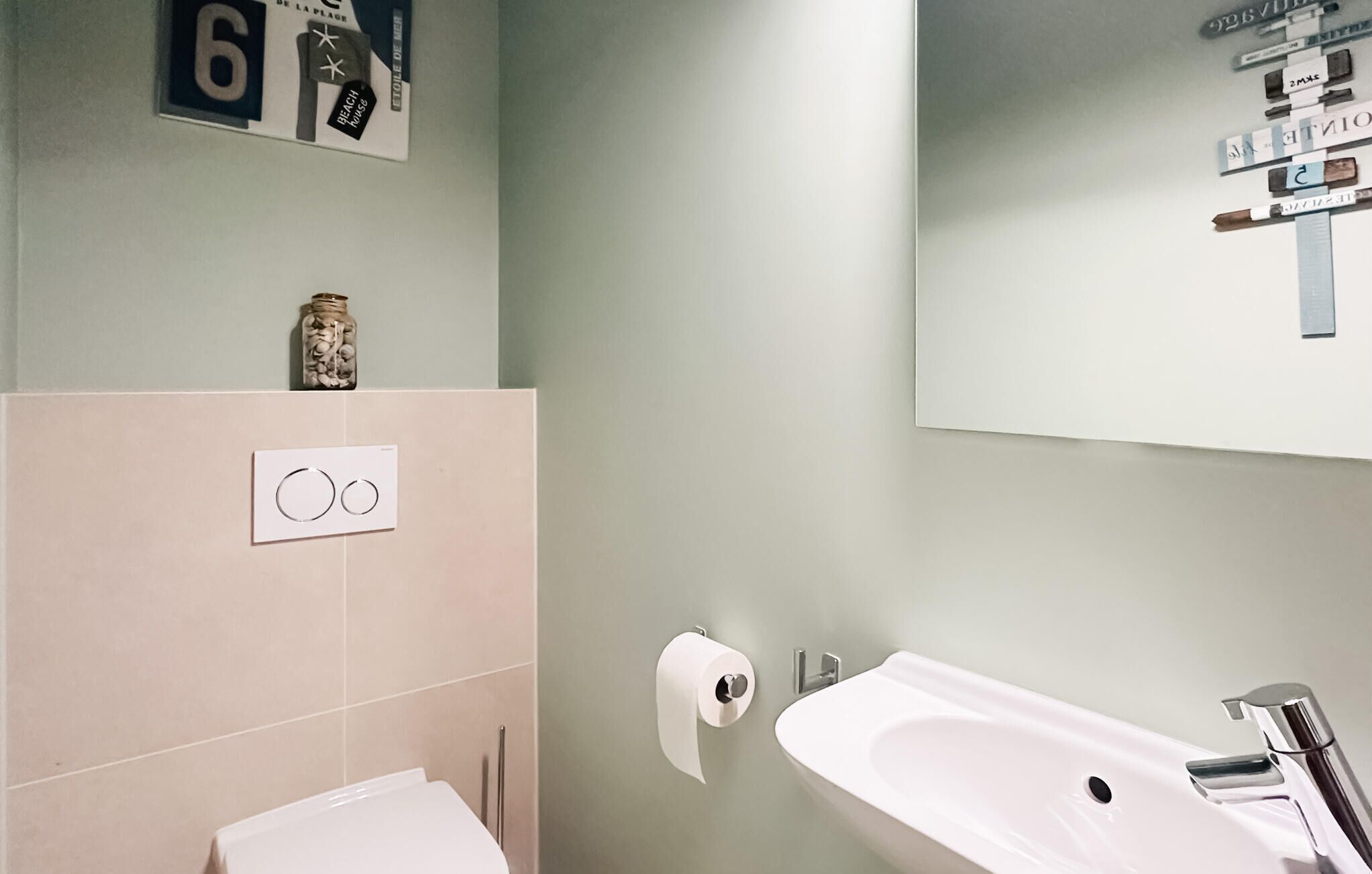 A bathroom with a toilet, sink, and a wall-mounted toilet paper holder.