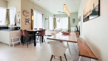Une cuisine moderne avec un coin repas, comprenant une grande table en bois, des chaises et un luminaire suspendu.