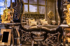 A luxurious bedroom with a large mirror reflecting a bed with patterned pillows, a tufted headboard, and a decorative wall hanging. - ABSOLUTE BEACHFRONT LUXURY ACCOMODATION
Entire home with Private Beach Access (Karitane)