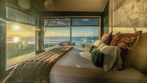 Un dormitorio con una cama grande, vista al océano y un diseño moderno.