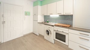 Een kleine keuken met een wasmachine, oven en een betegelde spatwand.