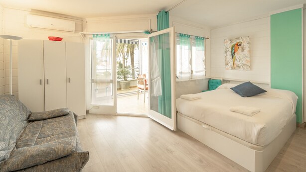 Een slaapkamer met een bed, een slaapbank en een schuifdeur naar buiten.