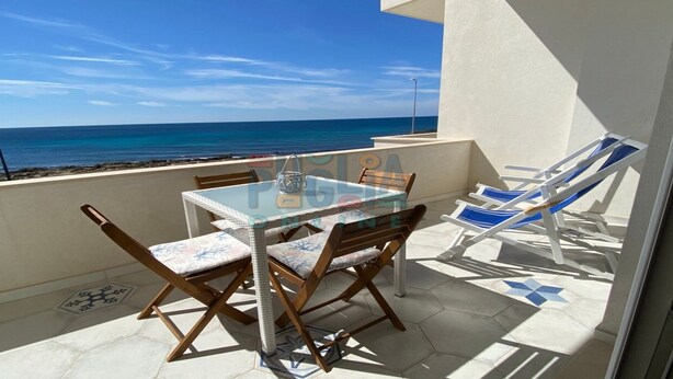 A balcony with a glass table and chairs, overlooking the sea. - Vacation home La Perla Salentina (Marina di Capilungo)