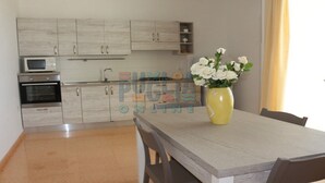 A modern kitchen with light wood cabinets, a microwave, an oven, and a dining area with a table and chairs. - Vacation home La Perla Salentina (Marina di Capilungo)