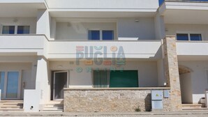 A modern two-story building with a stone facade and a green shuttered entrance. - Vacation home La Perla Salentina (Marina di Capilungo)