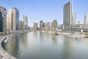 Stunning waterfront views of a bustling marina with boats docked and modern high-rise buildings in the background.
