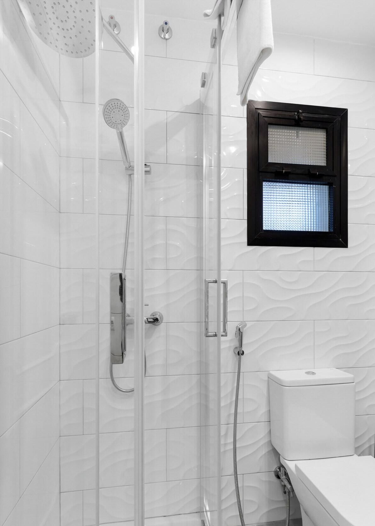 Ein Badezimmer mit Dusche, Toilette und einem Fenster mit Milchglasfenster.